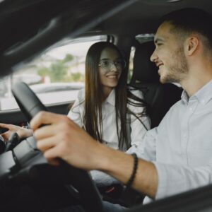 A smiling couple driving together in a car, enjoying their time on the road.